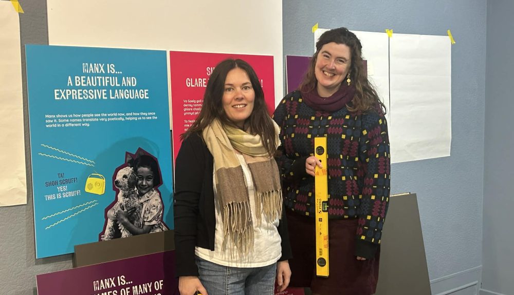 Colour photograph of Nicola Tooms and Ruth Keggin Gell prepare for the opening of ‘Mind Your Language’ Exhibition at the Manx Museum.